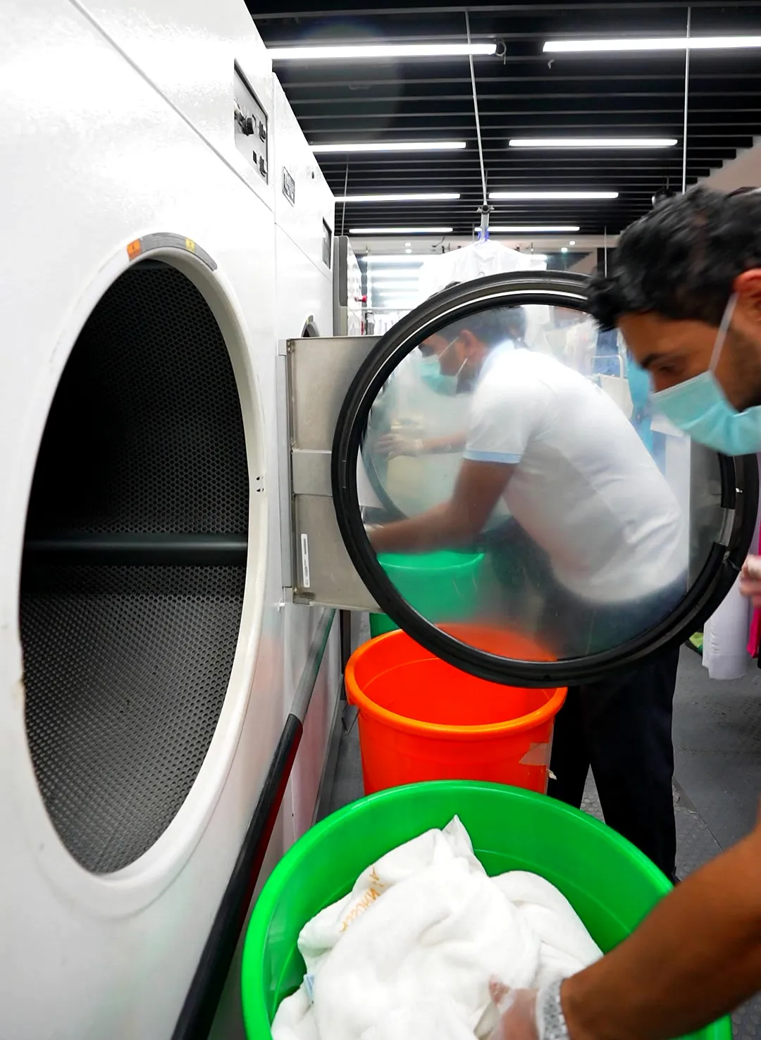 Large white fabrics being loaded into a washer at Grand Laundry, Abu Dhabi