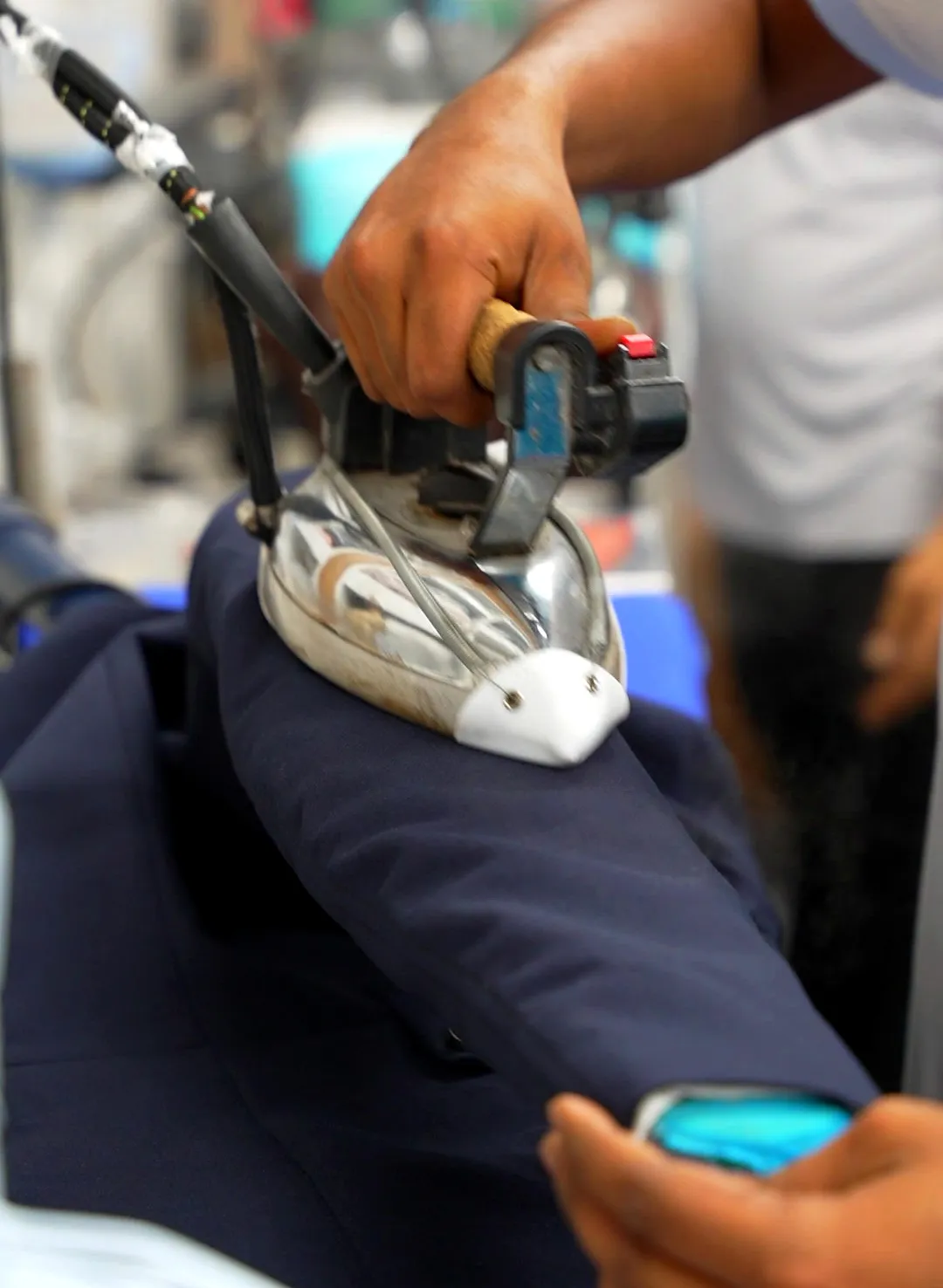 Steam iron pressing a navy garment at Grand Laundry, Abu Dhabi